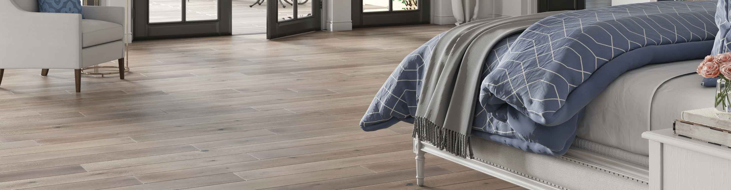 hardwood flooring in bedroom with bed and grey sheets and blue comforter 